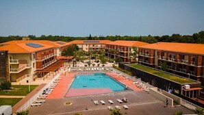 Un hotel con piscina central, varios balcones y un patio ajardinado.