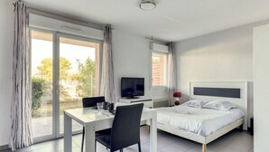 Habitación de hotel moderna con cama, escritorio, silla, televisor y ventana con cortinas.