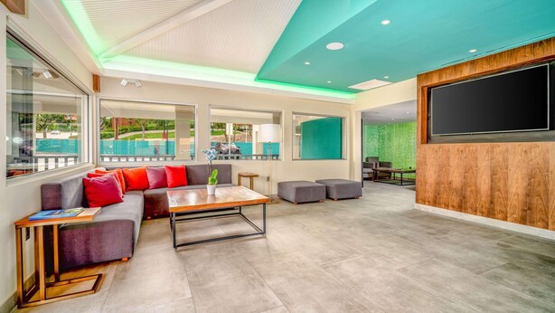 Un área de estar moderna con sofá, mesa, asientos, ventanas amplias y vista a una piscina.