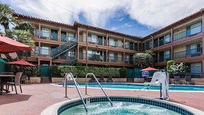 Un hotel con piscina, zona de estar al aire libre y un patio cubierto.