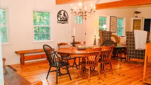 A dining area with a wooden table and chairs, a chandelier, and a bench.