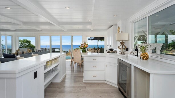 A spacious kitchen with a large island, white cabinetry, and a view of the ocean. - NEW! Ocean View Hawaii Vacation And Event Retreat (Kapaau)