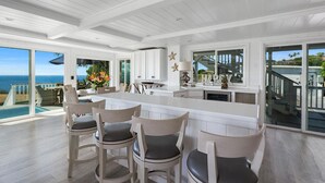 A spacious kitchen with a large island, white cabinetry, and a view of the ocean. - NEW! Ocean View Hawaii Vacation And Event Retreat (Kapaau)