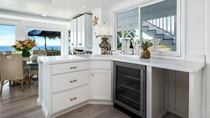 A modern kitchen with white cabinetry, a built-in oven, and a large window overlooking a staircase. - NEW! Ocean View Hawaii Vacation And Event Retreat (Kapaau)