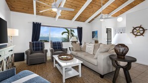 A living room with a wooden ceiling, a sofa, a coffee table, and a TV.