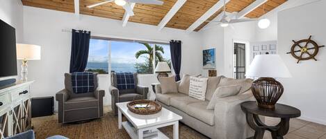 A living room with a wooden ceiling, a sofa, a coffee table, and a TV.