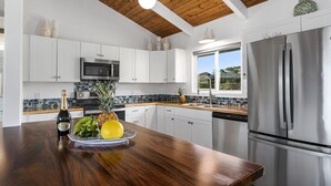 A modern kitchen with white cabinets, a stainless steel refrigerator, and a wooden ceiling.