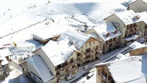 Een met sneeuw bedekt wintersportresort met chalethuizen, een skilift en een piste.