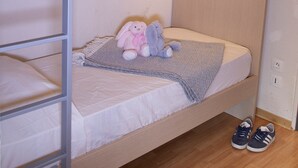 Una cama litera con cabecera, un par de auriculares colgando de la baranda superior y un par de zapatos en el suelo.