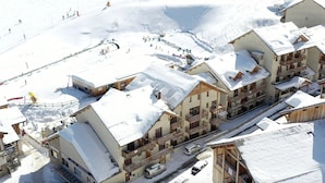 Un complejo turístico nevado con edificios de estilo chalet, un telesilla y una pista de esquí.