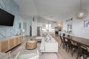 Une cuisine moderne avec des meubles blancs, un îlot central et un coin repas comprenant une table et des chaises en bois.