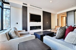 Una sala de estar moderna con chimenea, asientos cómodos y un televisor grande montado en la pared.