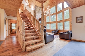 A spacious living area with a wooden staircase, large windows, and a stone fireplace. - 2nd Largest Home @ Camelback “Occupancy is 20 with day guests included” (Tannersville)