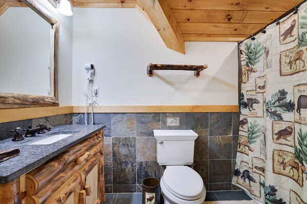 A bathroom with a wooden vanity, a toilet, and a shower curtain with animal prints. - 2nd Largest Home @ Camelback “Occupancy is 20 with day guests included” (Tannersville)