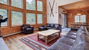 A spacious living room with large windows, a wooden ceiling, a leather sofa, a coffee table, and a sign for ice cream. - 2nd Largest Home @ Camelback “Occupancy is 20 with day guests included” (Tannersville)