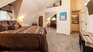 A bedroom with a large bed, a mirror, a desk, and a staircase leading to another room. - Snow Summit Dome Home. Walk to Snow Summit. HotTub (Big Bear Lake)