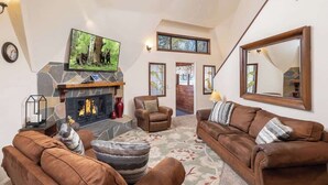 A living room with a stone fireplace, leather sofas, a television, and a large mirror. - Snow Summit Dome Home. Walk to Snow Summit. HotTub (Big Bear Lake)