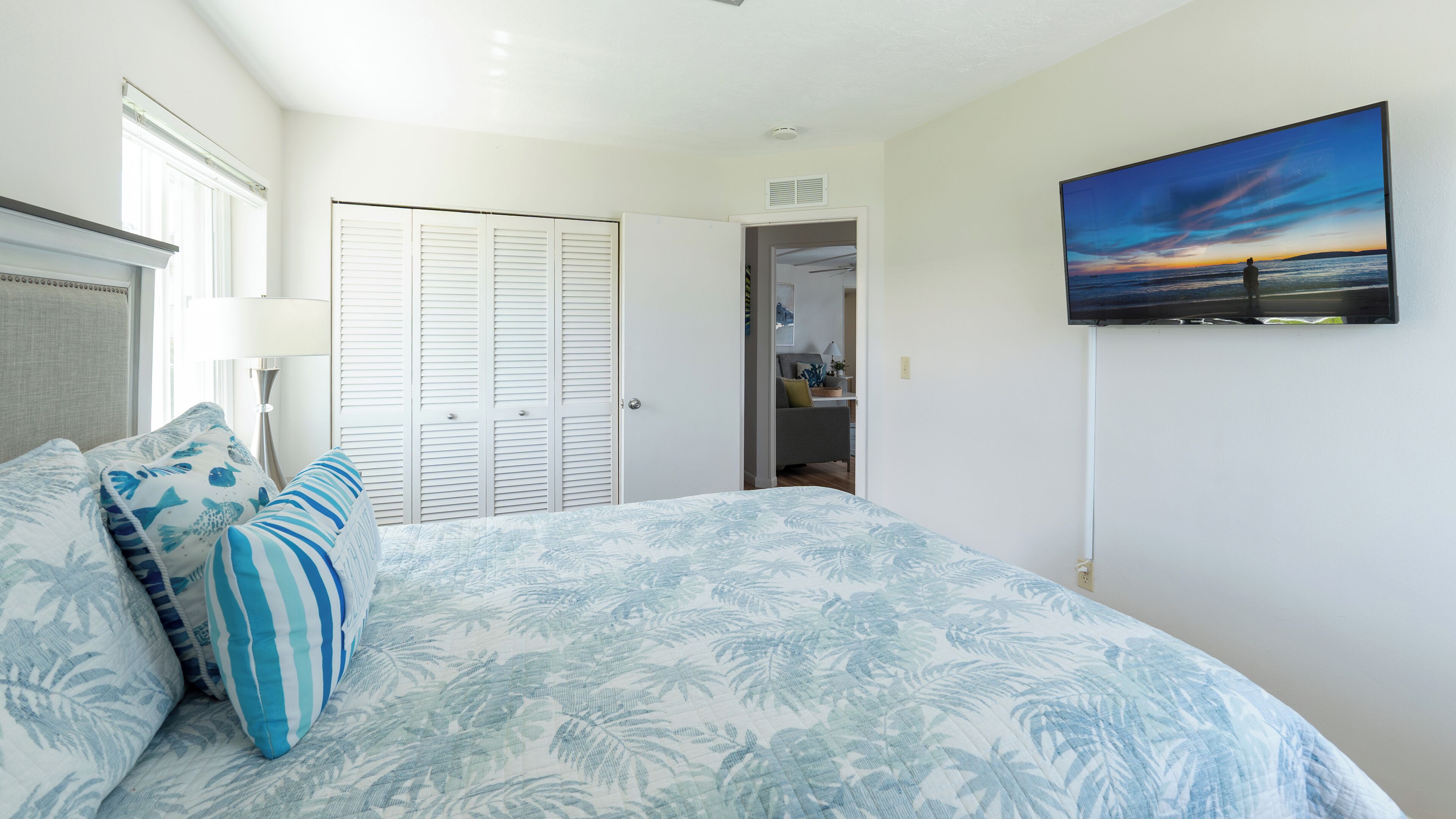 A bedroom with a bed, a wardrobe, a television, and a view of the outdoors.