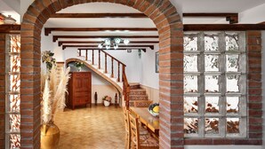 A spacious hallway with a wooden staircase, a large arched brick doorway, and a glass block window. - Beautiful private villa with A/C, WIFI, private pool, TV, terrace, panoramic view, close to Sorrento (Massa Lubrense)