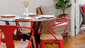 A dining area with a glass table, red chairs, a hanging light fixture, and a large plant. - Spacious 1 bedroom Ballard Apartment, Walk to Dining & Shops,  15 Min to Seattle (Seattle)