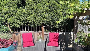 A patio area with two wicker chairs, a small table, and a red patterned rug. - Spacious 1 bedroom Ballard Apartment, Walk to Dining & Shops,  15 Min to Seattle (Seattle)