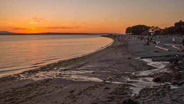 A beach with a sunset, sandy shore, and people walking. - Spacious 1 bedroom Ballard Apartment, Walk to Dining & Shops,  15 Min to Seattle (Seattle)