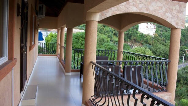 A covered balcony with stone pillars, a tiled floor, and a metal railing. - Remarkable 2-Bed Apartment in Kingston (Kingston)