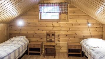 Un pequeño y acogedor dormitorio en ático con dos camas individuales, una silla de madera y una ventana con cortina a cuadros.