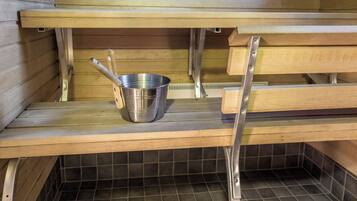 A sauna with wooden benches and a metal bucket on a shelf.