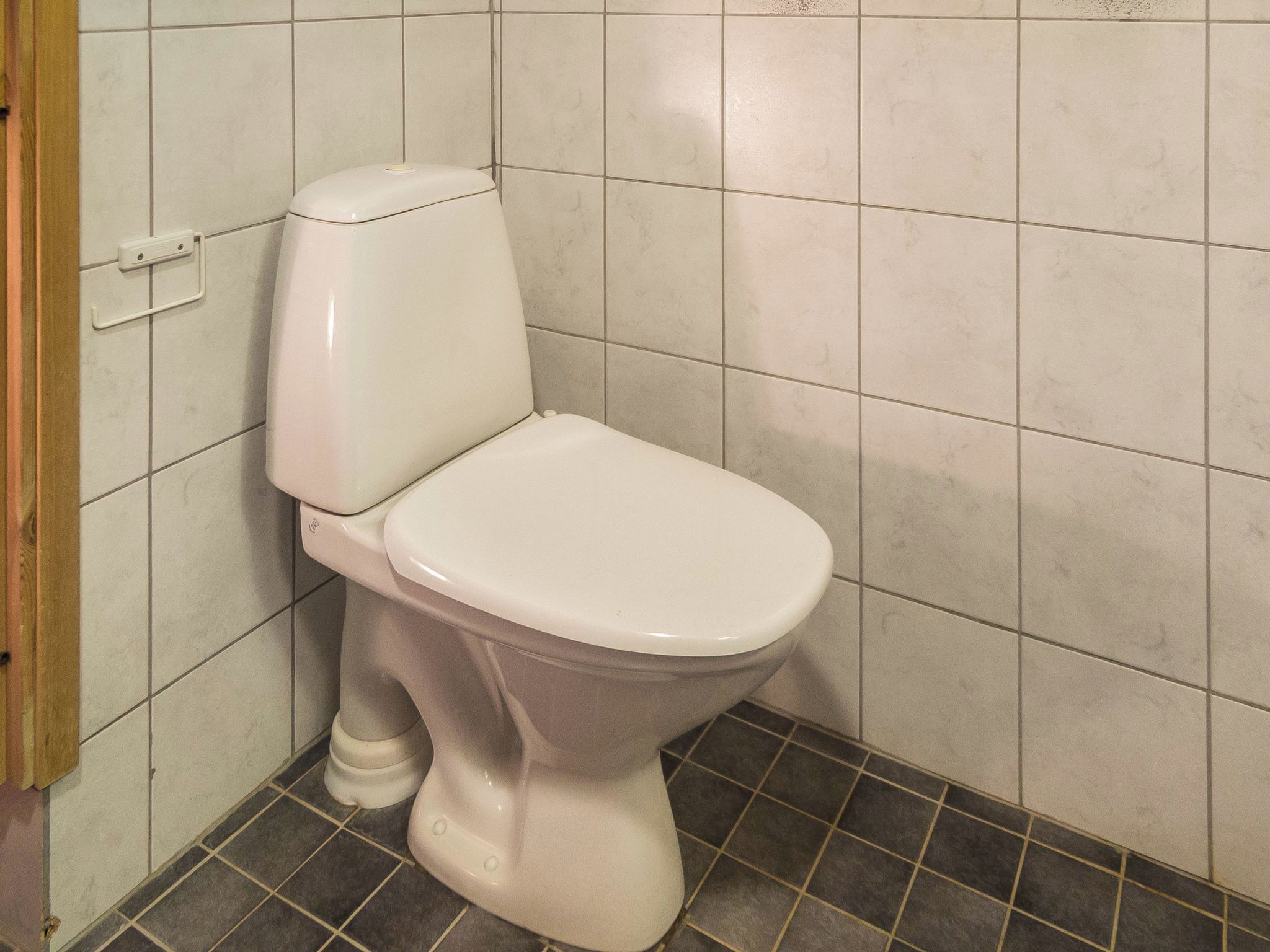 A white toilet in a bathroom with tiled walls and floor.