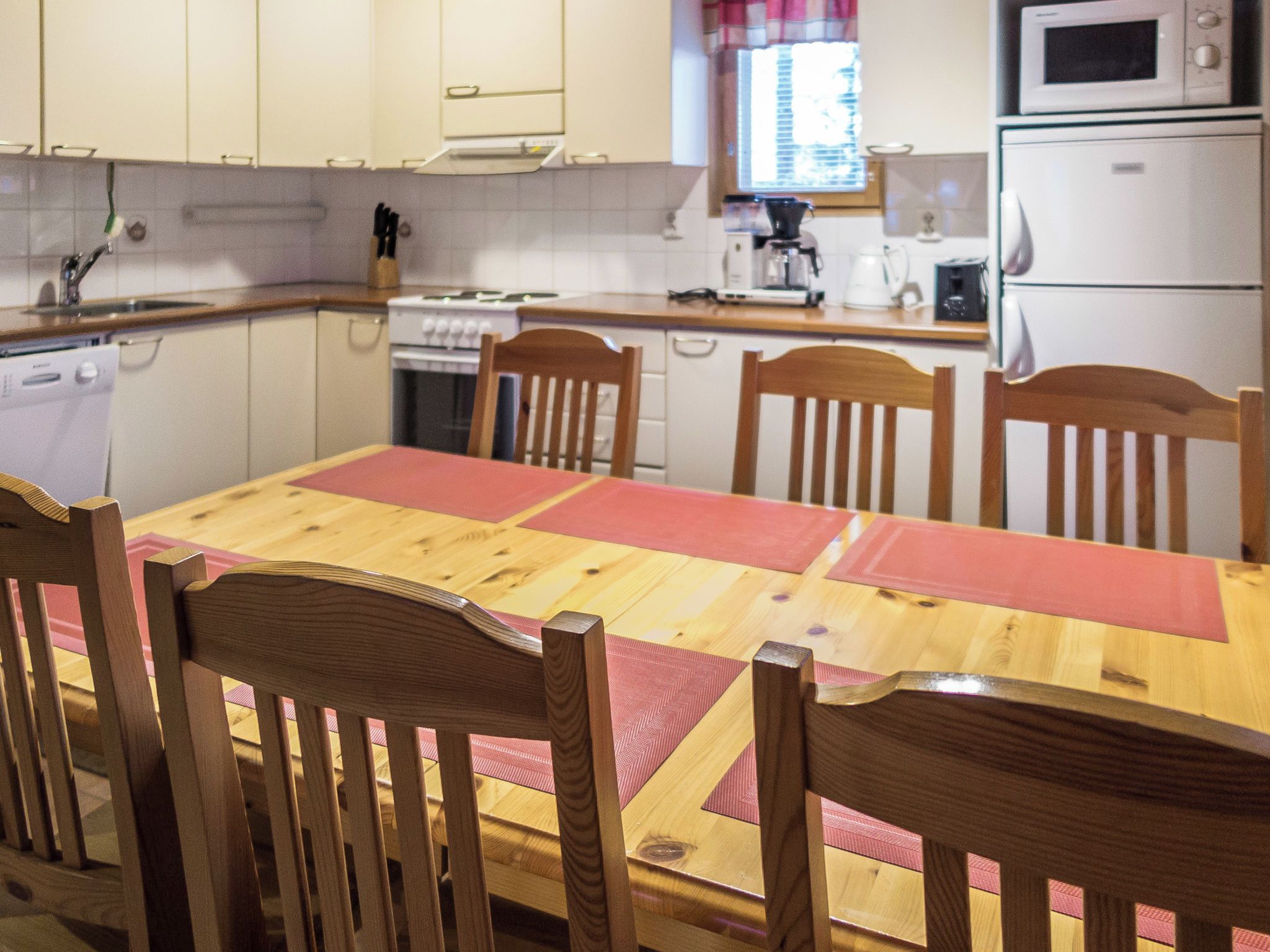 A compact kitchen with a dining table, chairs, and basic appliances.