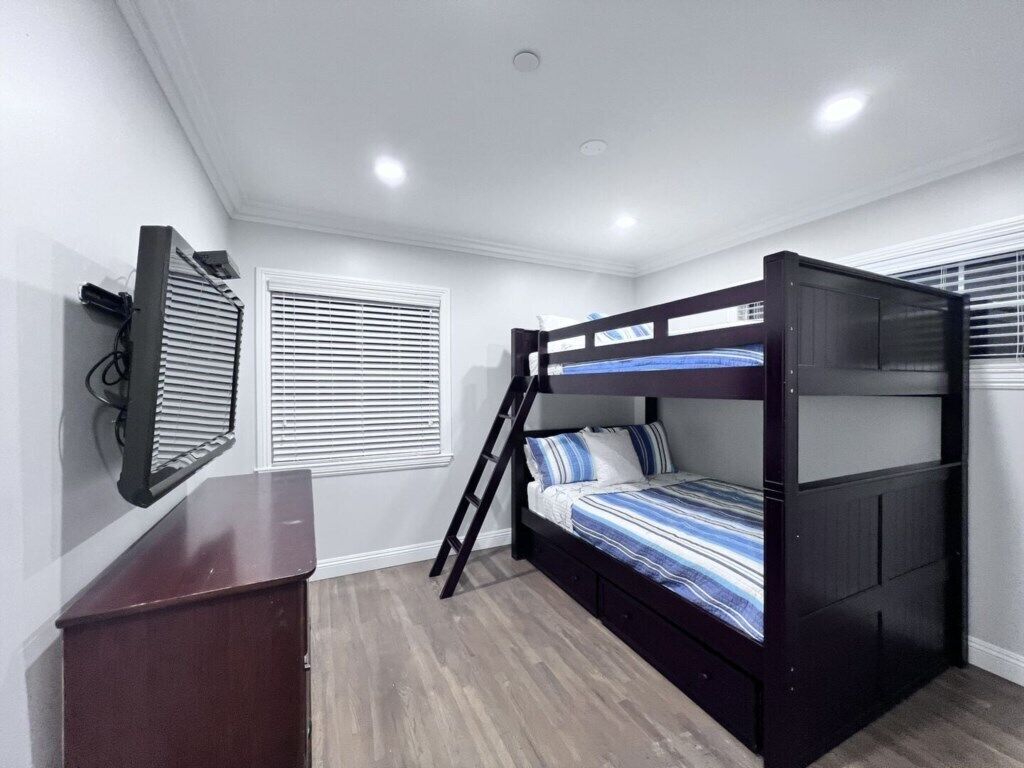 Habitación con literas, escritorio, ventana con persianas y luz en el techo.