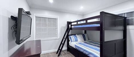 Habitación con literas, escritorio, ventana con persianas y luz en el techo.