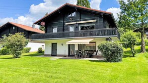 Un chalet de dos pisos con balcón, antena parabólica y césped bien cuidado.
