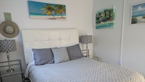 A bedroom with a bed, two bedside tables, a headboard, and wall art.