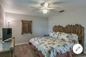 Relax in a serene bedroom with a large bed, bamboo headboard, and wall-mounted screen.