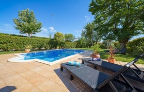 Una piscina con sillas de descanso y plantas en macetas.