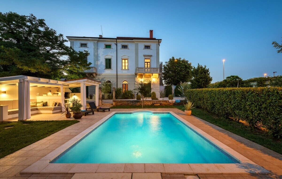 Un grand bâtiment à deux étages, avec une piscine en premier plan.