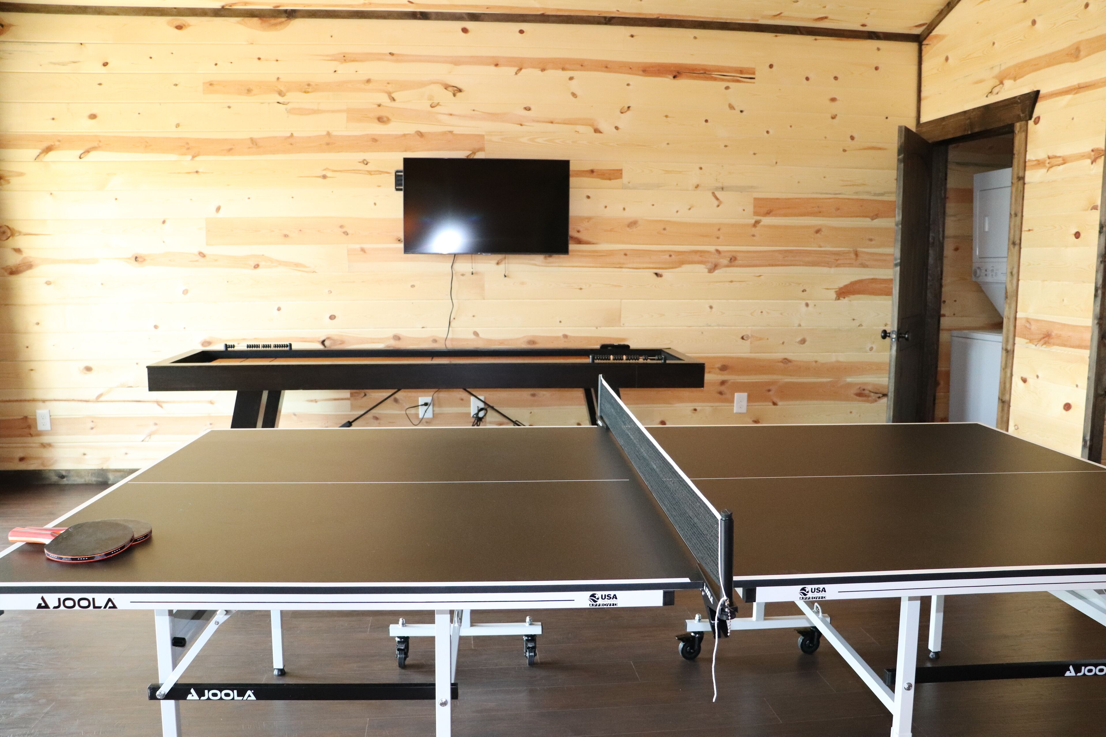 A ping pong table with a mounted television on the wall.
