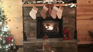 Ein Kamin mit Weihnachtssocken, einem Weihnachtsbaum und einer Schale mit einem kleinen Baum und einer Kerze.