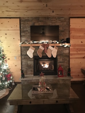 A fireplace with stockings, a Christmas tree, and a tray with a small tree and a candle.