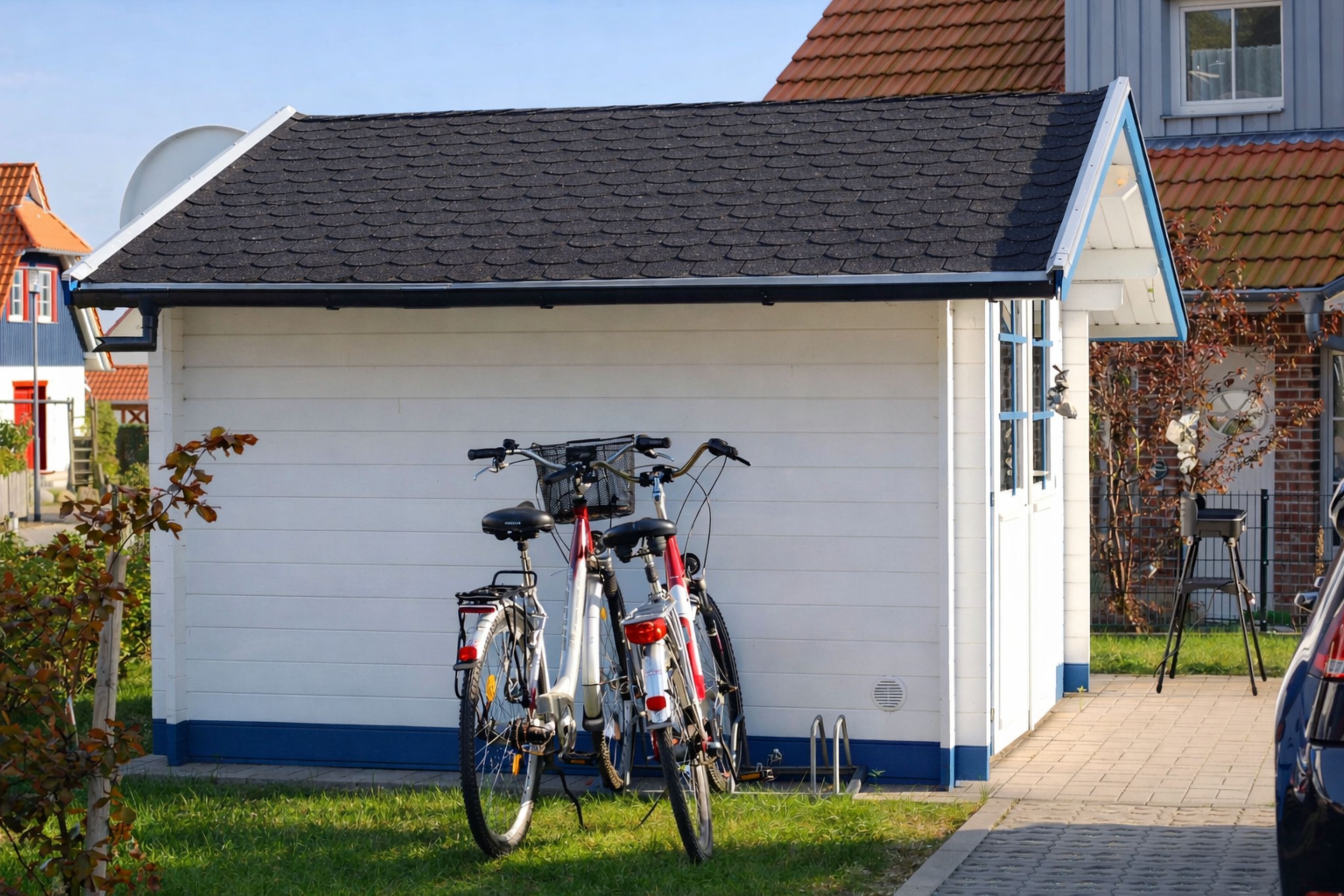 A small building with a sloped roof, two bicycles parked in front, and a car parked nearby.