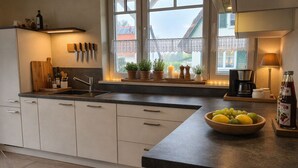 Una cocina moderna con un ventanal grande, un fregadero, una cafetera y un cuenco de fruta en la encimera.