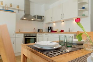 A dining table set with plates, glasses, and a vase with a flower. - 1.1 - Glienbergweg 26 Zinnowitz (Zinnowitz)