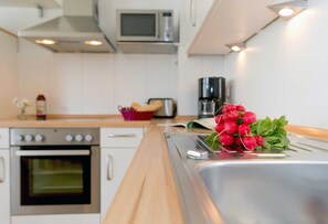 Une cuisine moderne équipée d’appareils électroménagers en acier inoxydable, d’un four à micro-ondes et d’une machine à café.