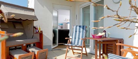 Et overdækket udendørs opholdsområde med en sofa, stole og et bord.