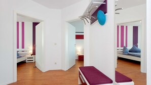 Ein modernes Schlafzimmer mit Holzboden, einem weißen Bett mit violettem Kopfteil, einem Nachttisch und einem Beistelltisch.