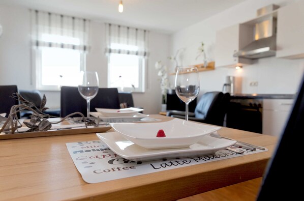 A dining table with a placemat labeled "Coffee Latte Mocha," two wine glasses, and a dessert plate with a strawberry.