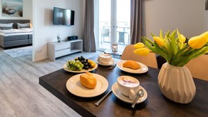 Ett modernt hotellrum med en matplats, en platt-TV, ett stort fönster och ett matbord som är dukat för frukost.