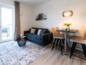 Un salon moderne avec un canapé, des fauteuils, une table à manger et une grande fenêtre.